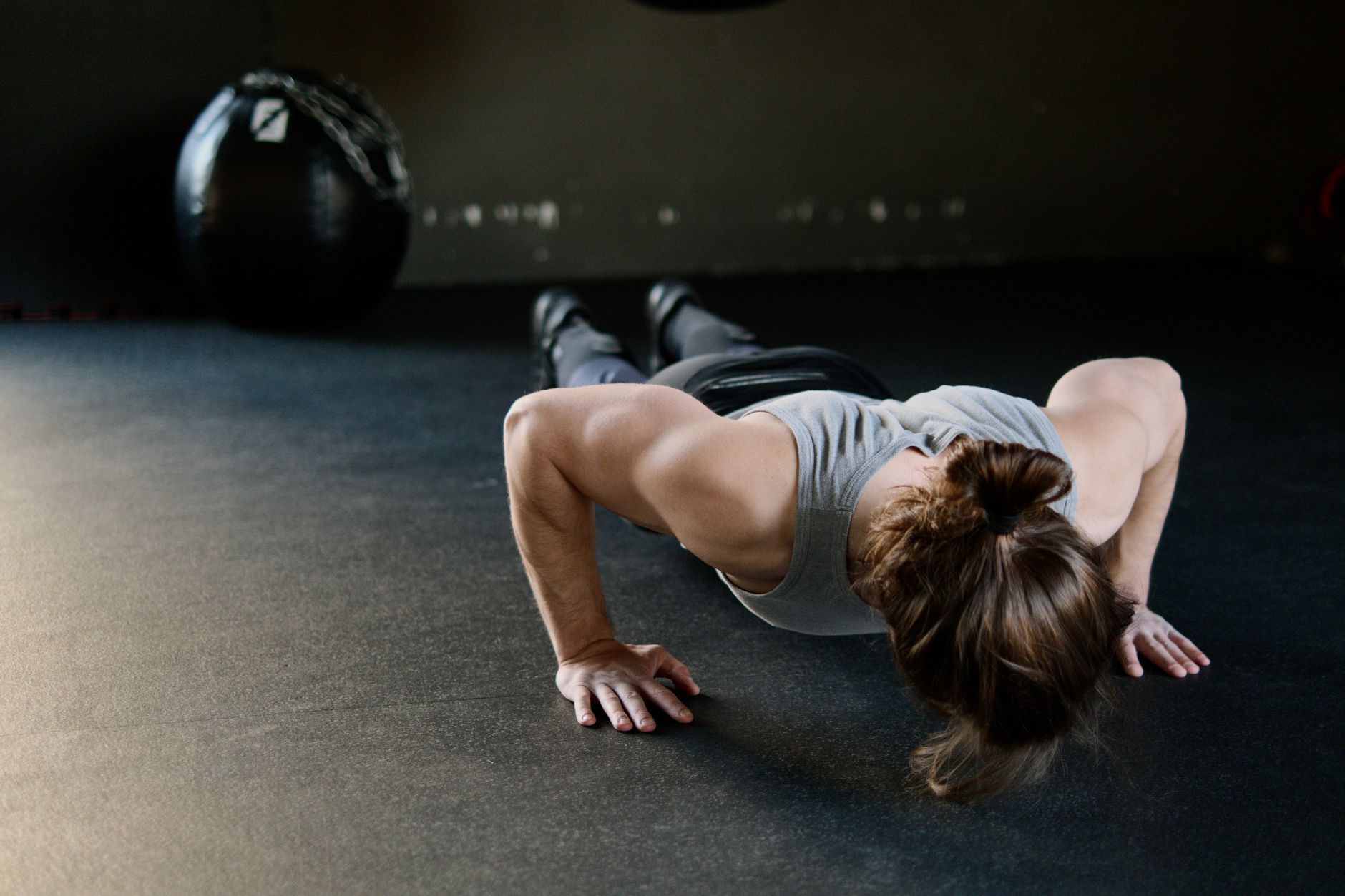 Strong male engaged in push-up exercise on gym floor, showcasing upper body strength.