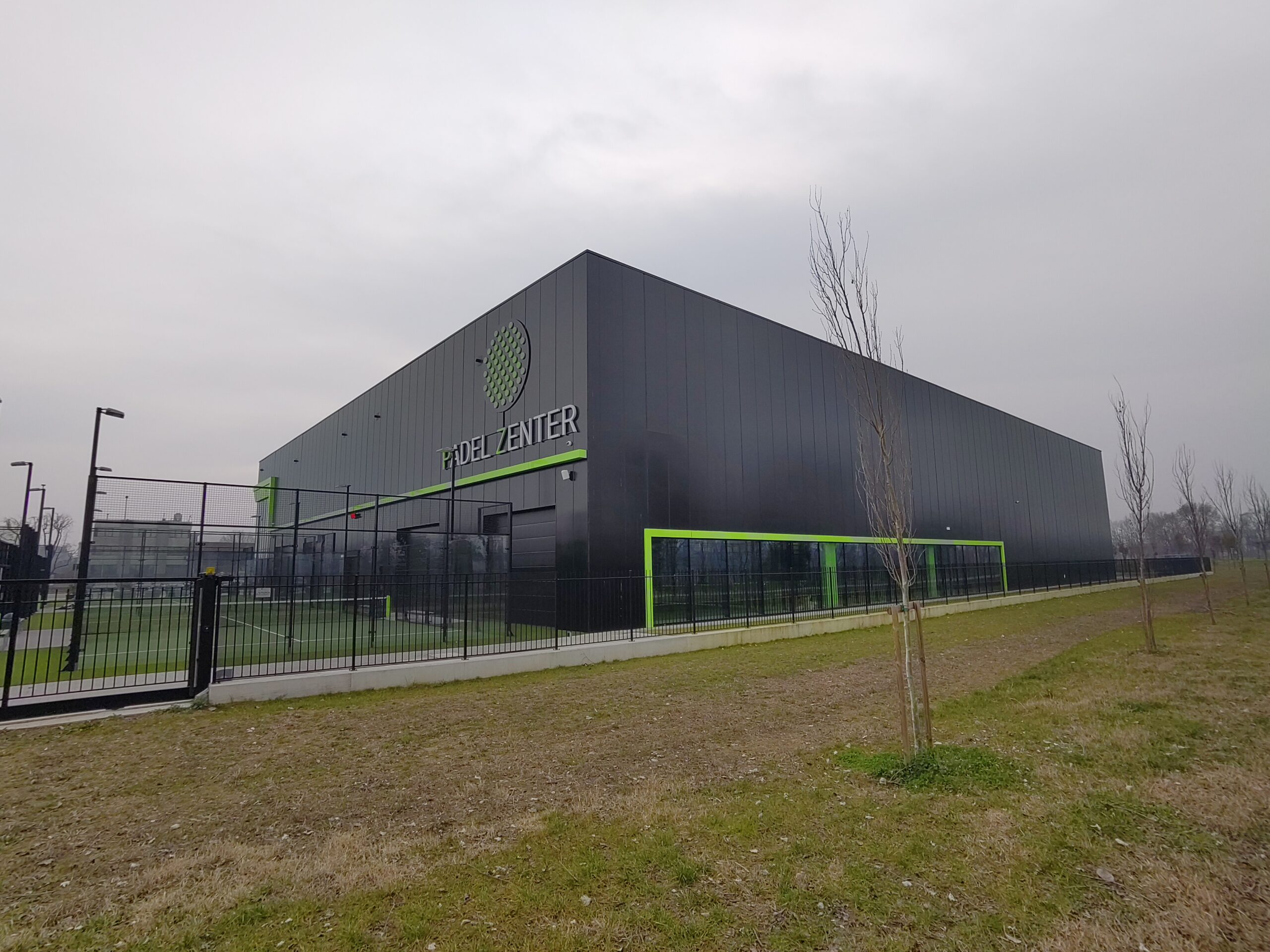 Gedung besar bernama Padel Zenter dengan lapangan padel di sampingnya di Italia.