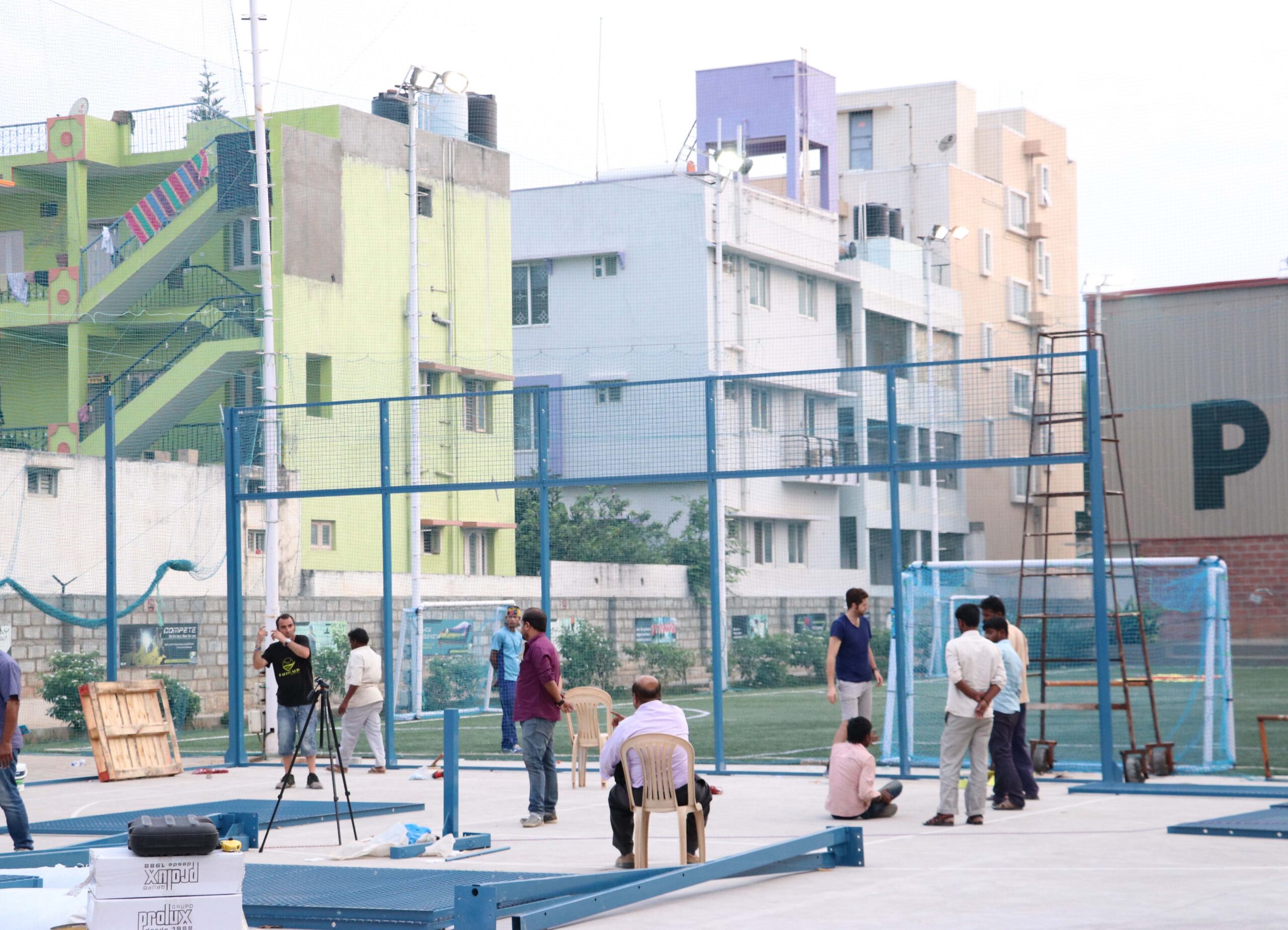 Pekerja dan warga berkumpul di lokasi pembangunan lapangan padel baru di kawasan permukiman padat.