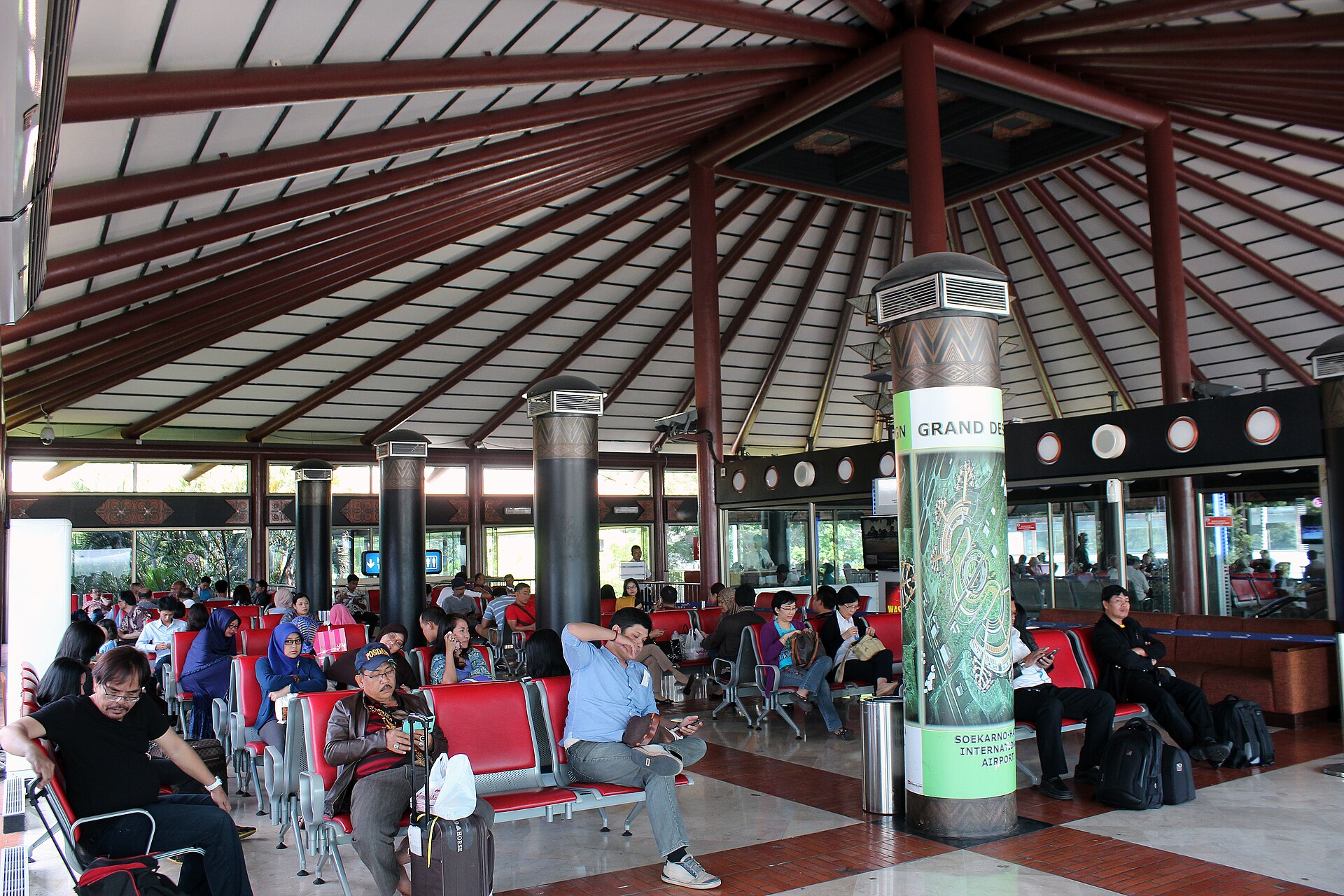 Penumpang dengan koper dan tas ransel menunggu di ruang tunggu gerbang Terminal 2 Bandara Soekarno-Hatta