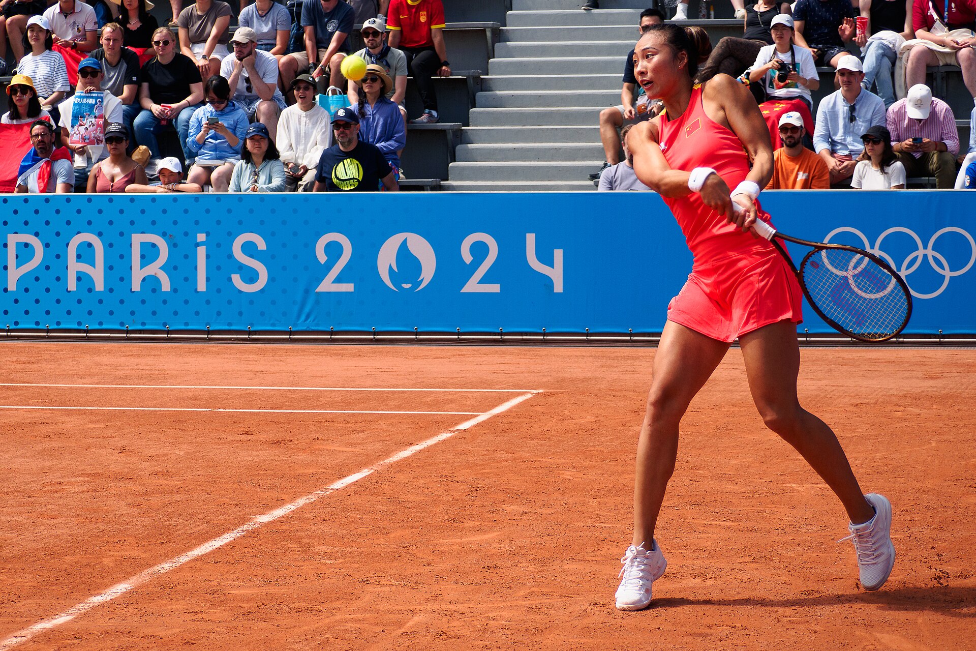 Zheng Qinwen memukul backhand mengenakan seragam merah tim China (foto arsip ilustratif Olimpiade Paris 2024, bukan dari China Open 2026).